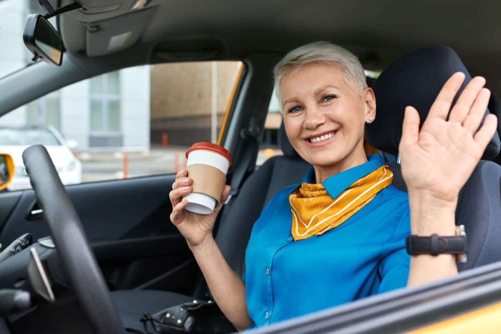 Mulher sorrindo com café no carro